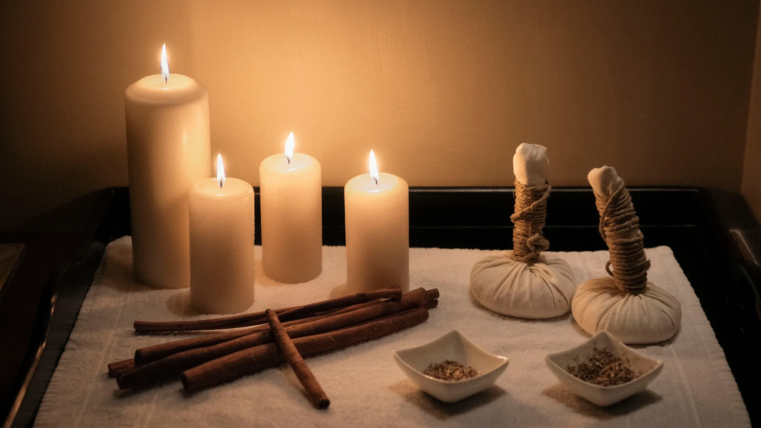 Treatment tray with lit candles, cinnamon sticks, herbal compresses and herb bowls