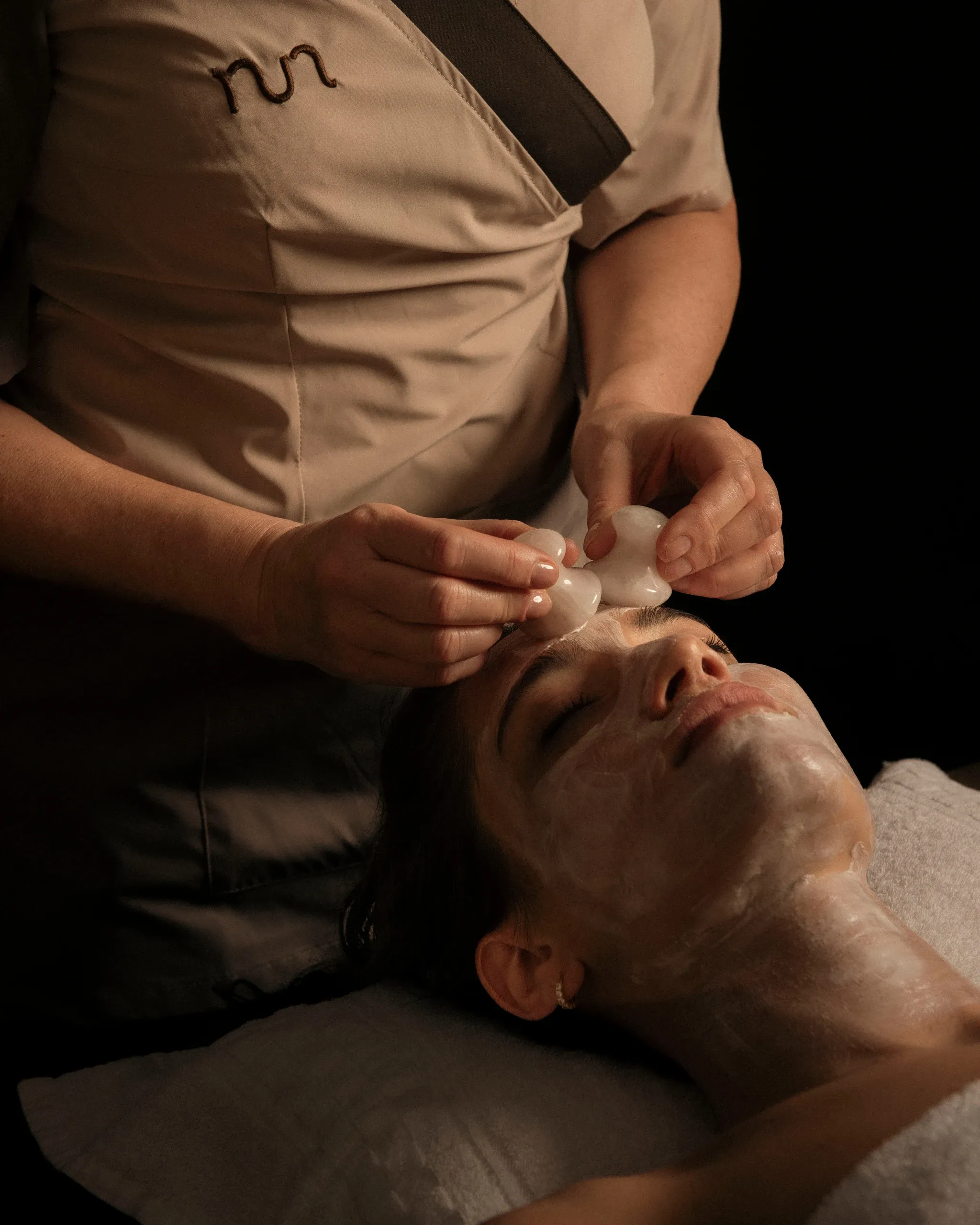 Gua-sha facial treatment with therapist hands and stone tools
