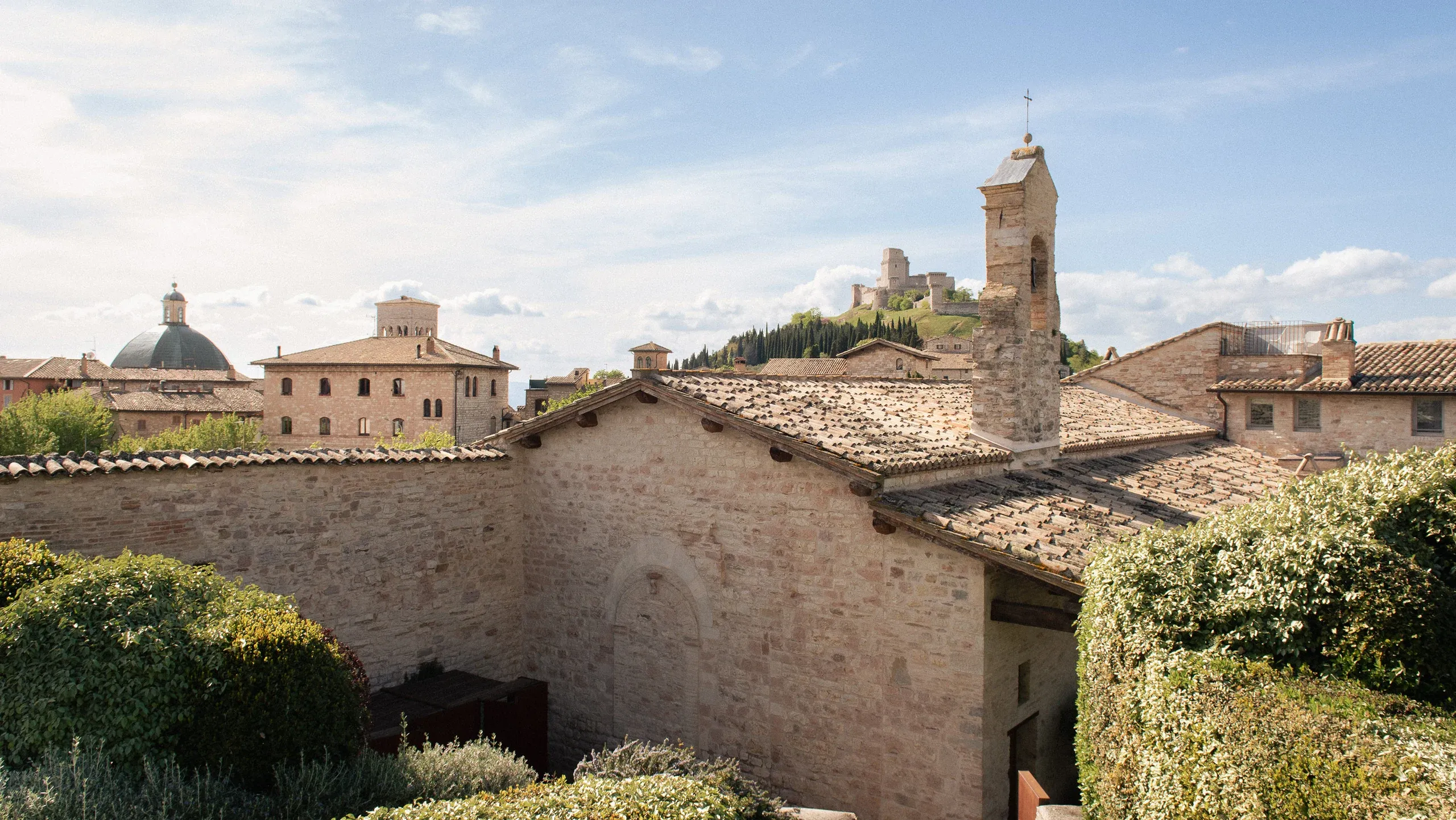Stone rooftops with bell tower and Rocca on hilltop
